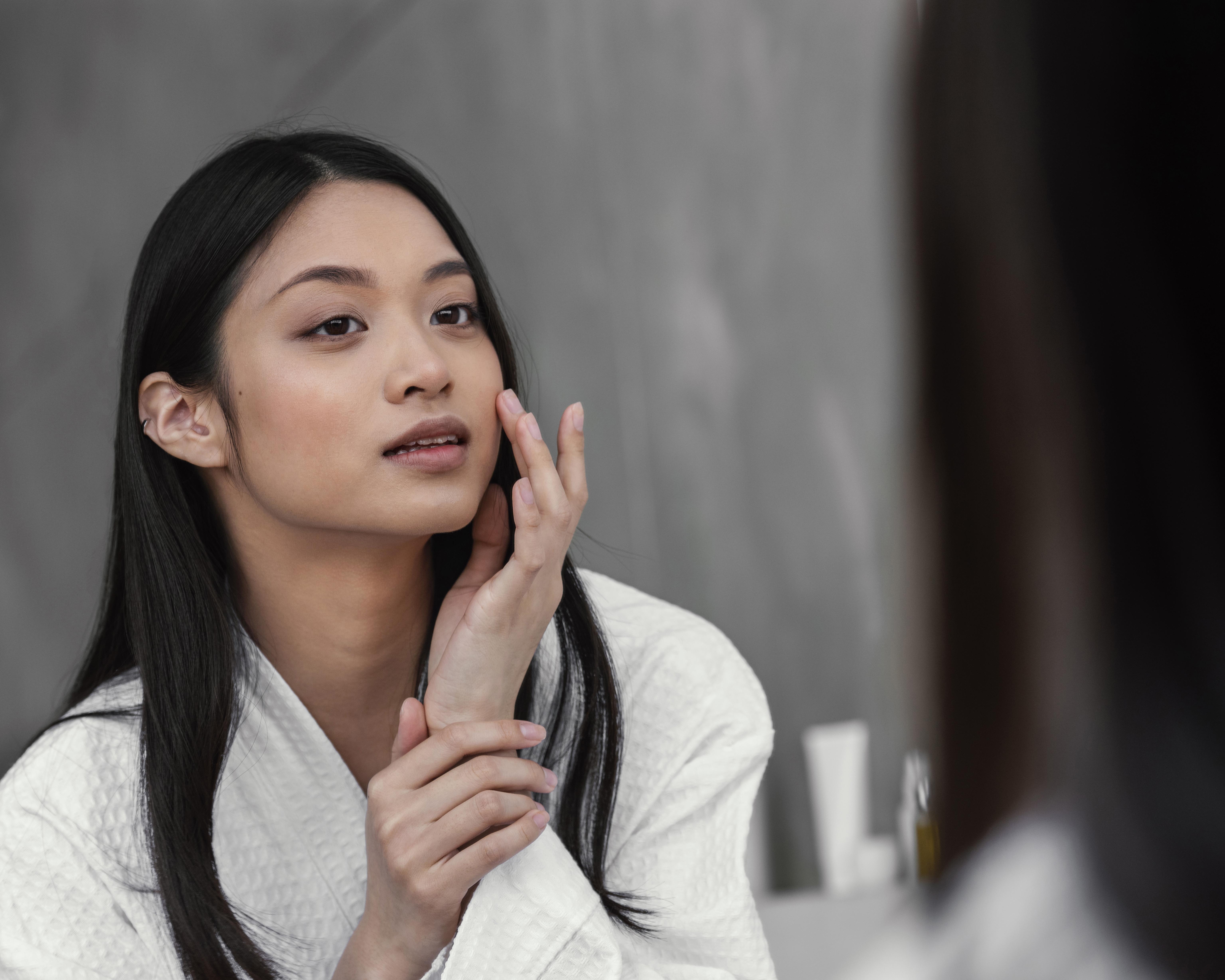 Woman checking her skin for acne